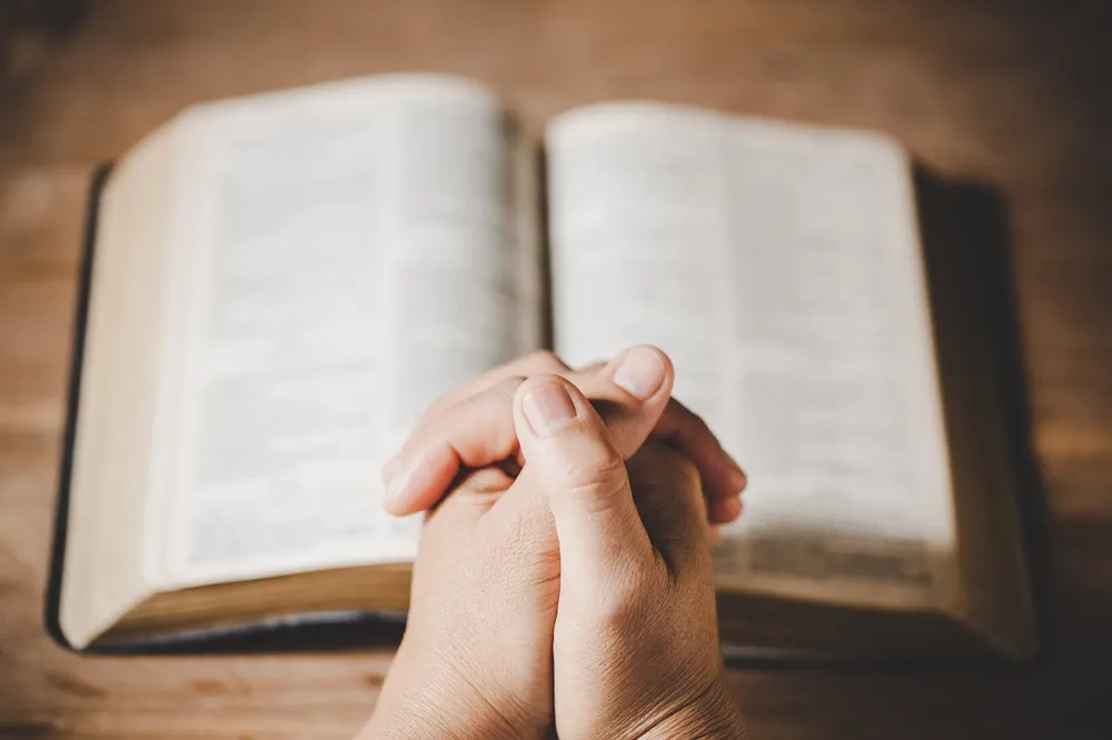 Manos en oración sobre una Biblia